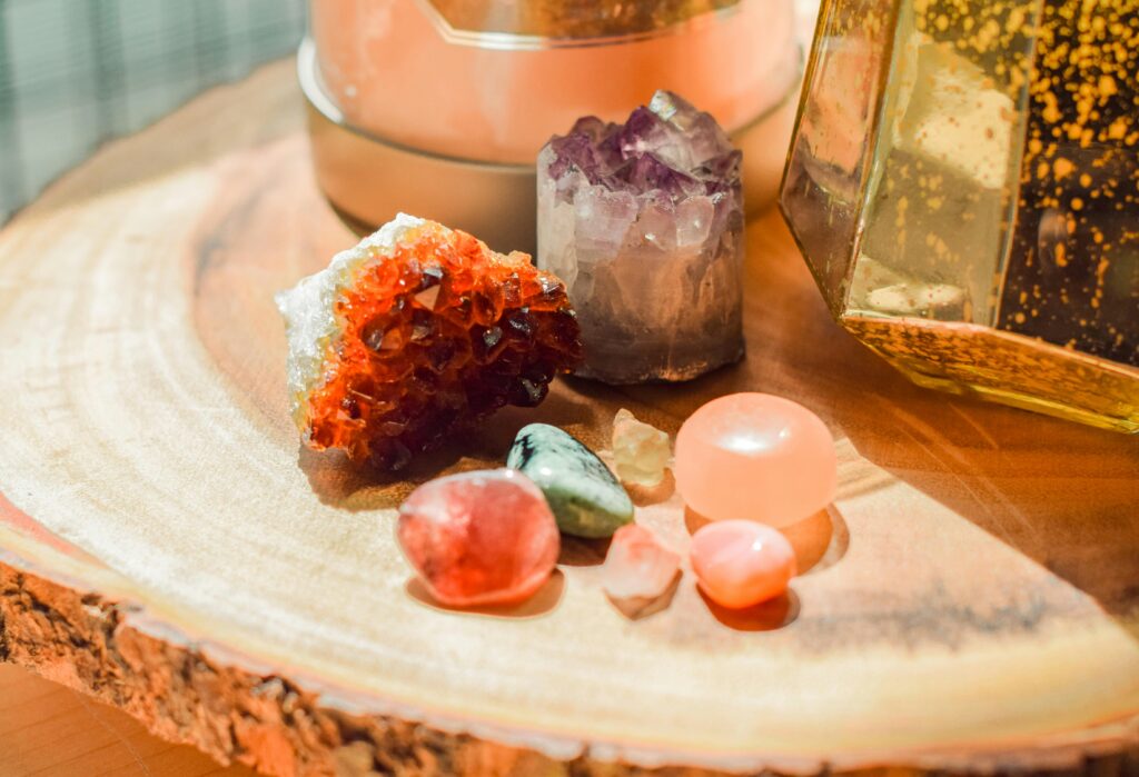 Colorful healing crystals on wooden slab, featuring amethyst and vibrant red stone.