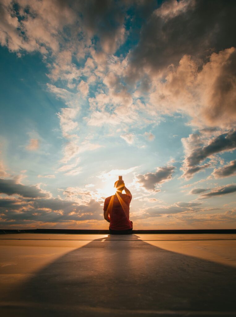 Person taking a photo of a vibrant, dramatic sunset with clouds and blue sky overhead.
