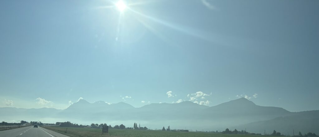 Fraser Valley travelling on the highway going East into the bright sun. The mountains are visible in the background